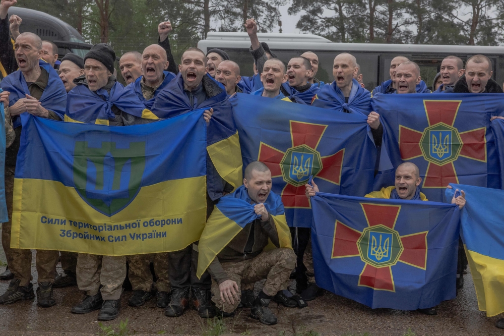 Released Ukrainian prisoners of war (POWs) react as they pose for a group photograph following a prisoner exchange at an undisclosed location, in the Chernihiv region on May 15, 2026. (Photo by Roman PILIPEY / AFP)