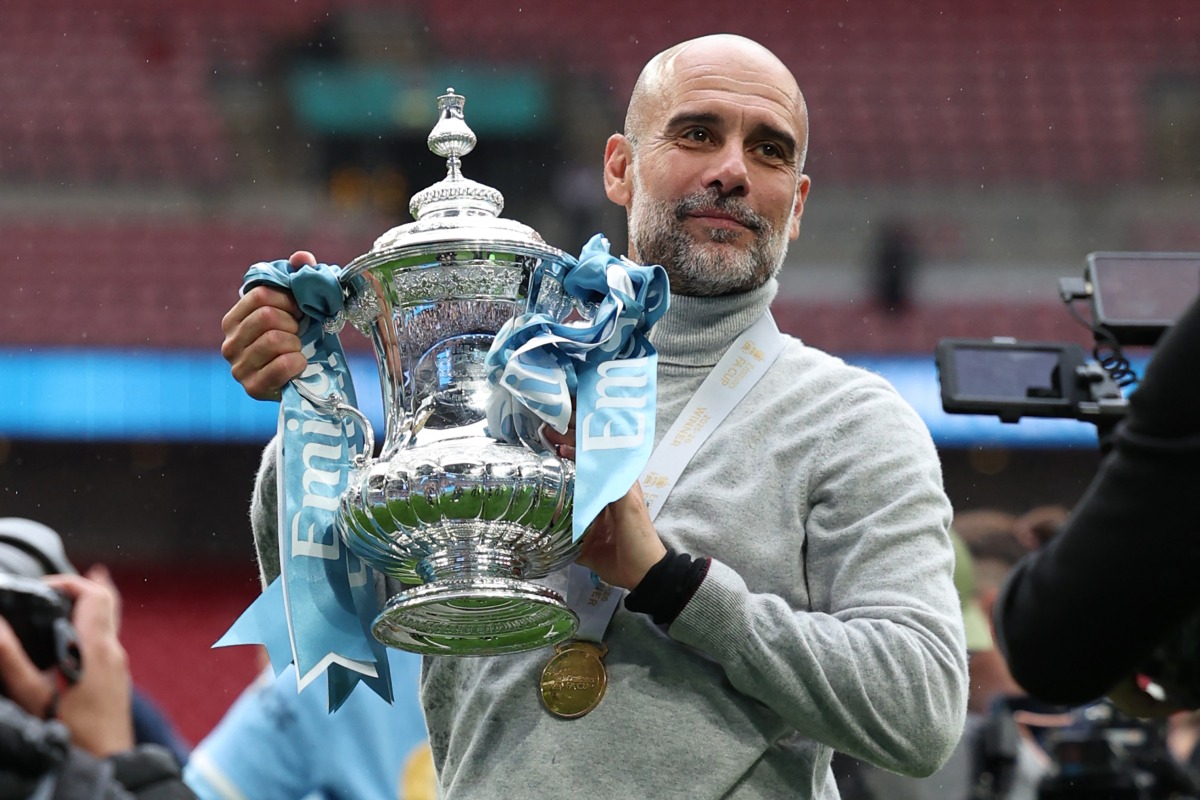 Manchester City's Spanish manager Pep Guardiola poses with the trophy on the pitch after the English FA Cup final football match between Chelsea and Manchester City at Wembley stadium in London, on May 16, 2026. Photo by ADRIAN DENNIS / AFP