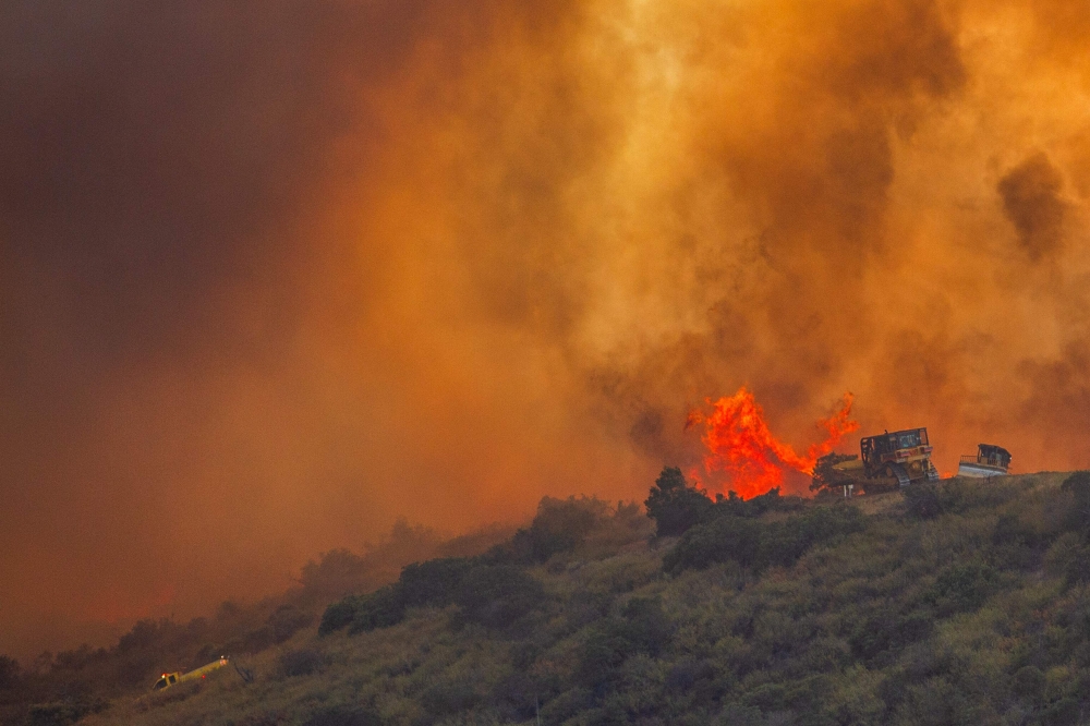 Fire fighters use a bulldozer to combat the Sandy Fire as it burns on a hill at a residential area in Simi Valley, California (Photo by Apu Gomes / AFP)