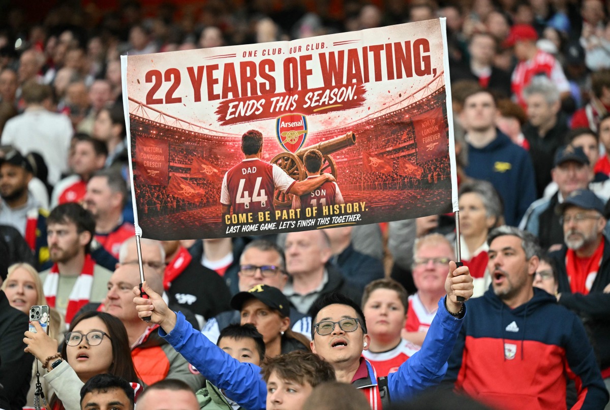 (FILES) A hopeful Arsenal fan holds up a banner reading '22 years of waiting' ends this season, during the English Premier League football match between Arsenal and Burnley at the Emirates Stadium in London on May 18, 2026. (Photo by Glyn KIRK / AFP)