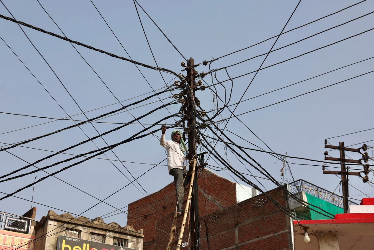 A worker repairs a street light in Varanasi on May 22, 2026. (Photo by Niharika KULKARNI / AFP)