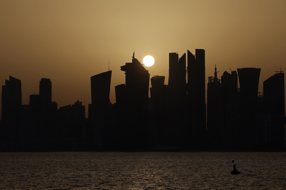 Skyscraper buildings are silhouetted against the setting sun in Doha on May 24, 2026. (Photo by Karim Jaafar / AFP)