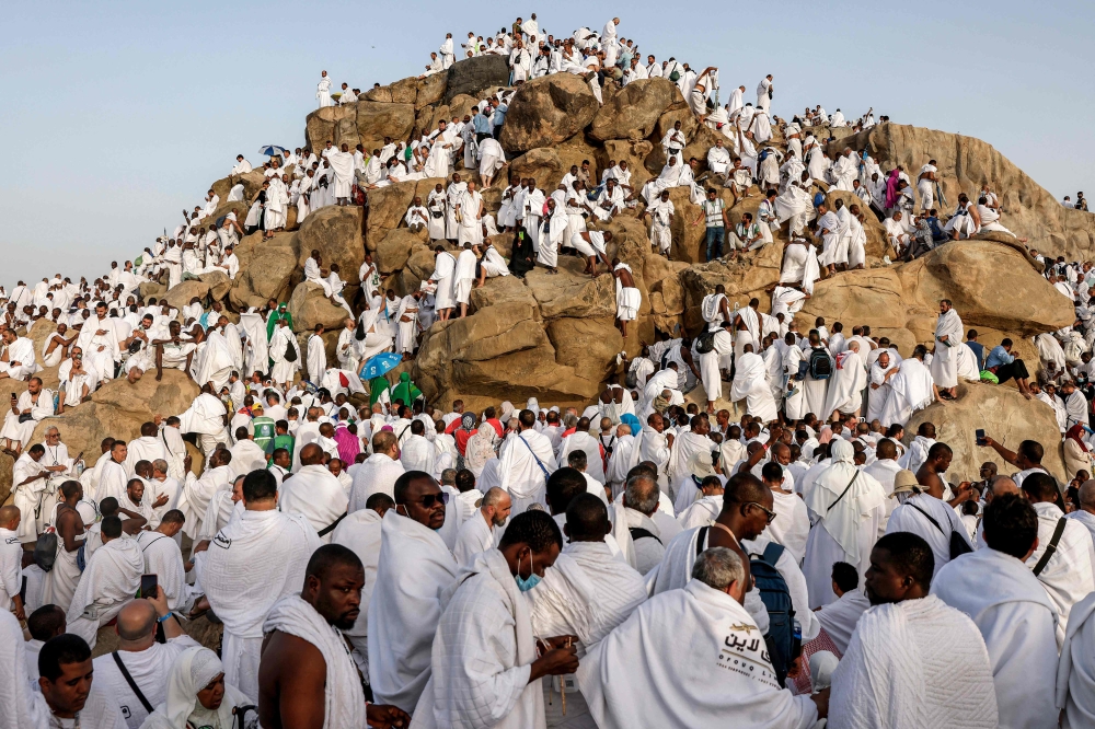 Muslim pilgrims pray at dawn on Saudi Arabia's Mount Arafat, also known as Jabal al-Rahma or Mount of Mercy, during the climax of the Hajj pilgrimage on May 26, 2026. (Photo by Zain JAAFAR / AFP)