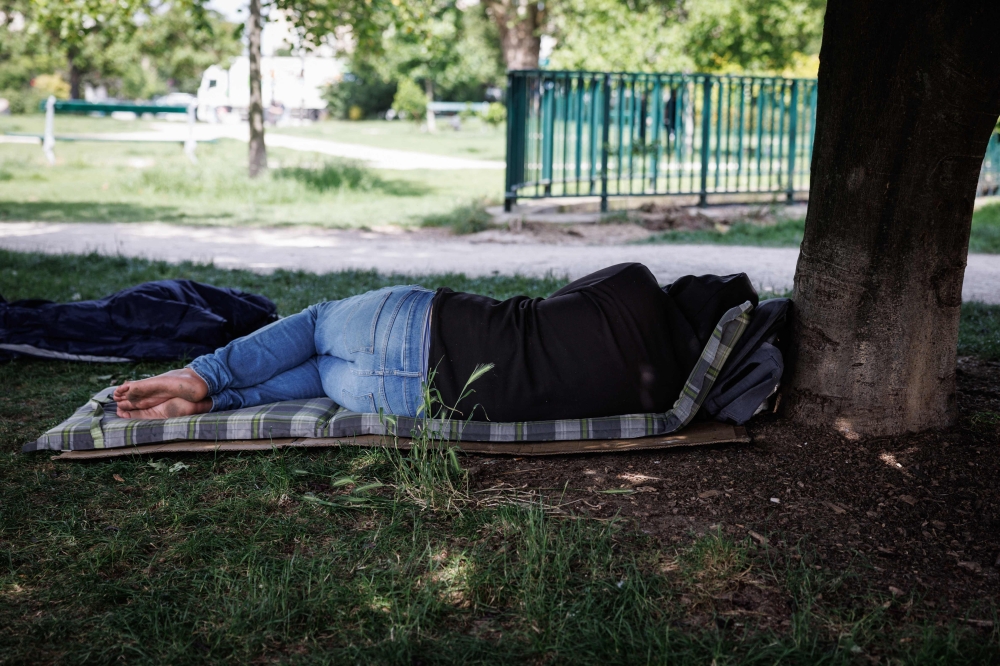 A person lies on a mattress under a tree in a park, in Paris on May 29, 2026 as a heatwave hits France.  (Photo by Simon Wohlfahrt / AFP)