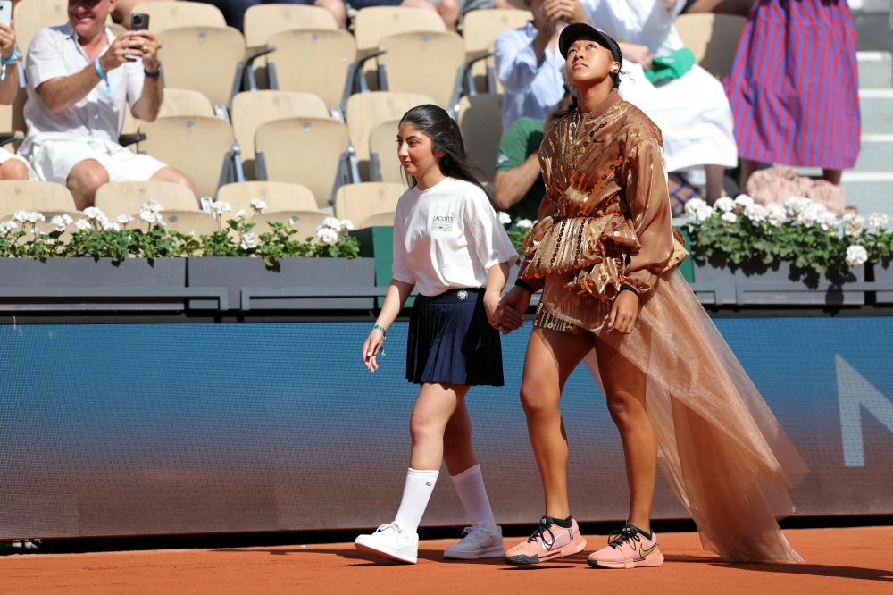 Japan's Naomi Osaka walks on court with a mascot for her women's singles match at the Roland-Garros Complex in Paris on May 30, 2026. (Photo by Thomas Samson / AFP)