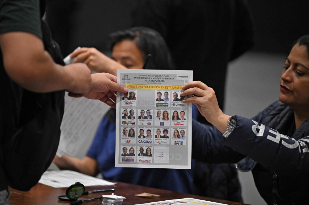 A voter receives his ballot a polling station during the presidential election in Bogota on May 31, 2026. (Photo by Luis ACOSTA / AFP)