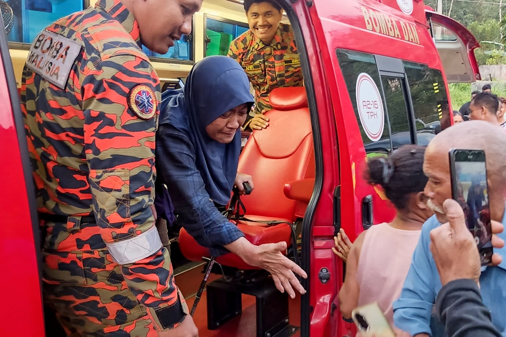 This handout photo taken and released by Perak's Fire and Rescue Department on June 6, 2026, shows rescuers assisting Jaslinda Saludin (2nd L) after she was found in a forested area in central Malaysia's Perak state. (Photo by Handout / Perak's Fire and Rescue Department / AFP)