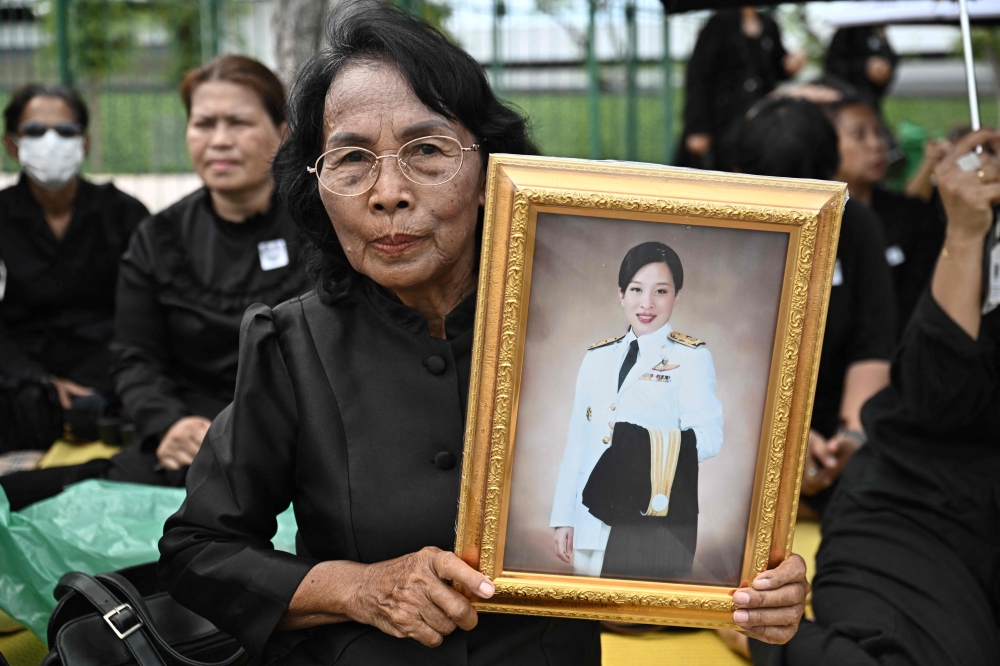 A mourner holds a portrait of late Thai Princess Bajrakitiyabha Mahidol outside the Grand Palace in Bangkok on June 13, 2026. (Photo by Lillian Suwanrumpha / AFP)