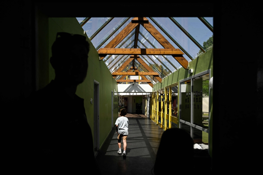 (Files) A child walks along the glass-roofed corridor of the Isle Verte primary school on May 28, 2026. (Photo by Philippe Lopez / AFP)