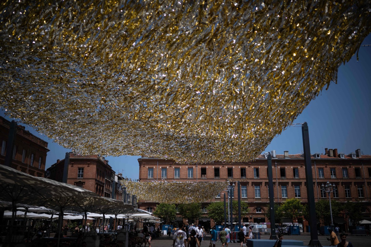 People walk through the Capitole square covered by an installation to provide shade, in Toulouse on June 19, 2026. Photo by Lionel BONAVENTURE / AFP