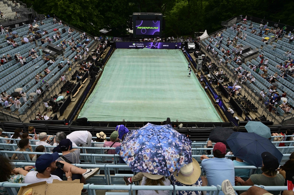 The court is covered and spectators use umbrellas as rain started after the first women's singles semi-final match at the WTA500 Berlin Tennis Open tournament in Berlin on June 20, 2026. (Photo by John MacDougall / AFP)