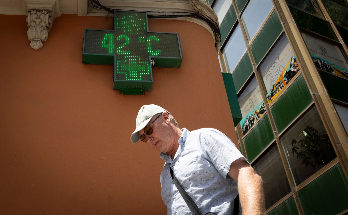 A tourist walks past a sign that reads 42 degrees Celsius in Palma de Mallorca on June 20, 2026, on the eve of the start of the first official heatwave of this summer. Photo by Jaime REINA / AFP