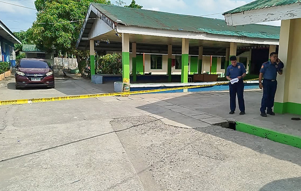 Policemen stand near the crime scene of a school compound after a shooting incident at a high school compound in Tacloban City, Leyte province on June 22, 2026. (Photo by Noel Sianosa / AFP)