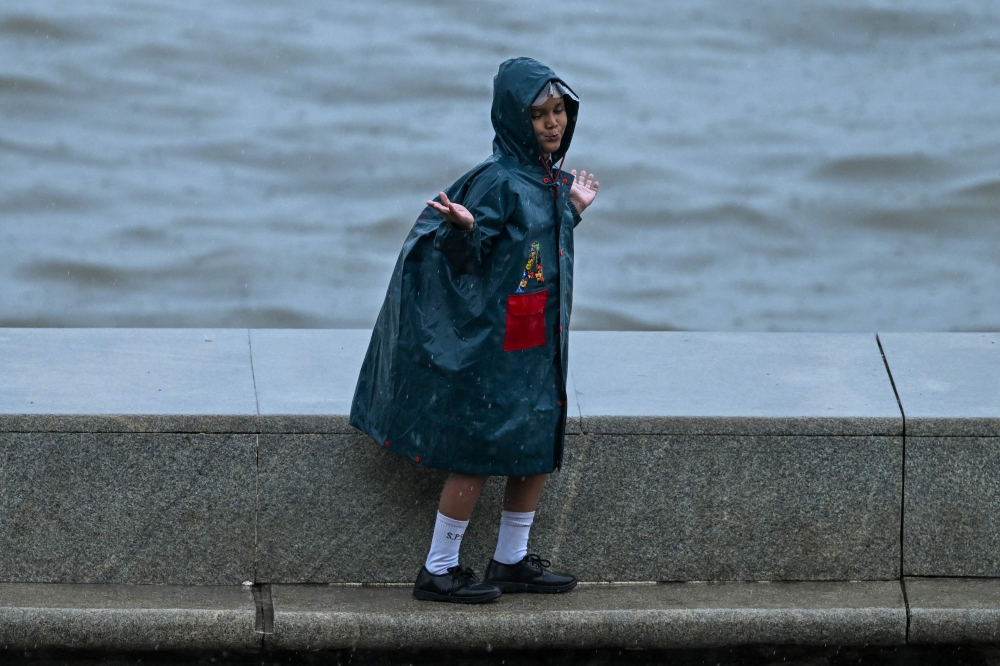 A child enjoys during rainfall while going to school, in Mumbai on June 23, 2026. (Photo by Punit Paranjpe/ AFP)
