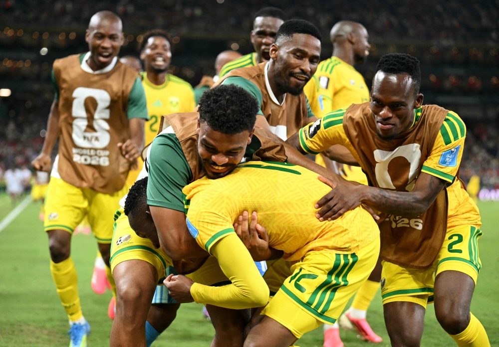 South Africa's forward #12 Thapelo Maseko is hugged by teammates while celebrating scoring his team's first goal. (Photo by Yuri Cortez / AFP)
