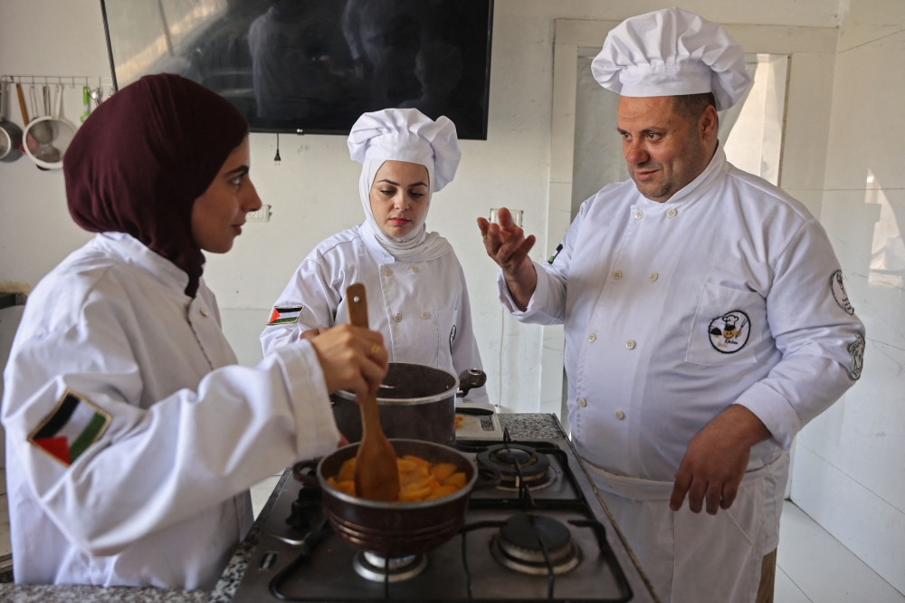 Palestinian youth learn the basics of cooking at the Smile Kitchen Academy, in the Rimal neighborhood of Gaza City on June 24, 2026. (Photo by Omar Al-Qattaa / AFP)