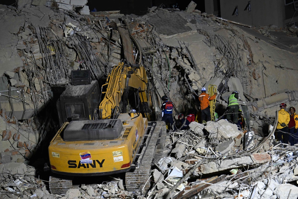 Rescue teams operate heavy machinery at the site of a collapsed building in Caracas on June 25, 2026, following earthquakes. (Photo by Juan BARRETO / AFP)