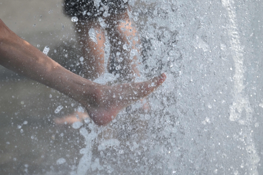 People cool off with the water of a fountain in Berlin on June 28, 2026. (Photo by Ralf Hirschberger / AFP)