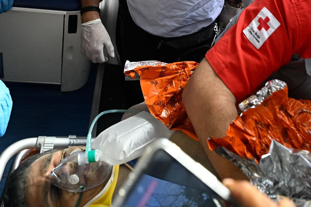 An international rescue team assists a survivor of Venezuela's twin earthquakes in Catia La Mar, La Guaira State, Venezuela on July 2, 2026, eight days after the quake. Hernan Gil, a 43-year-old security guard, had been buried in the booth of the seven-story building where he worked in Catia La Mar, a coastal area in the state of La Guaira devastated by the disaster. (Photo by Federico PARRA / AFP)
 