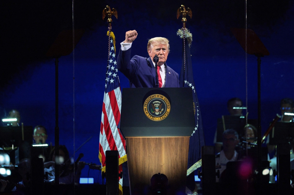 US President Donald Trump raises his fist while speaking at 