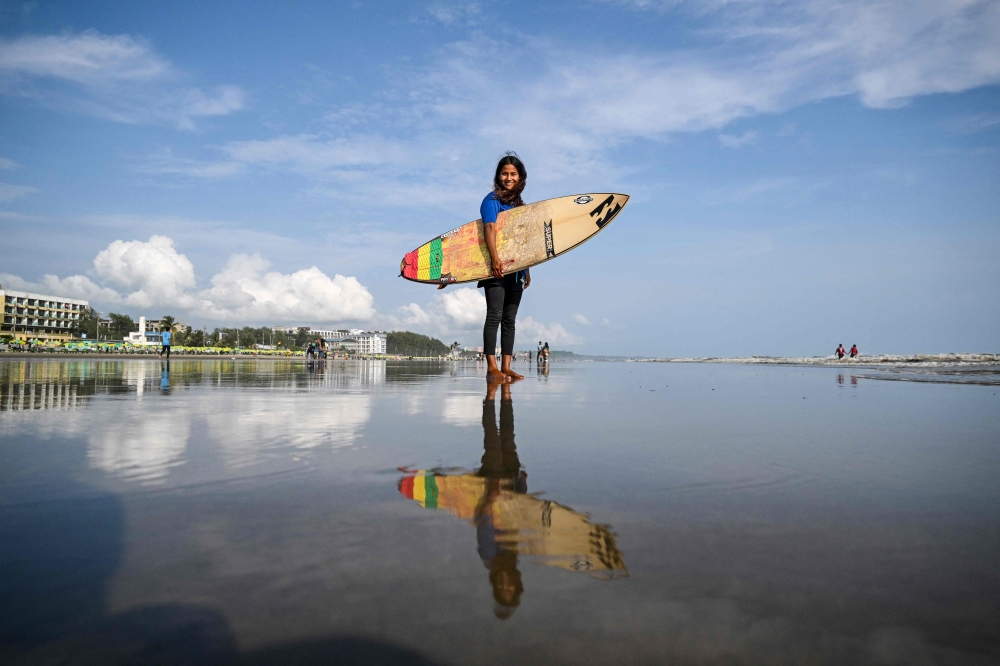 This photograph taken on June 19, 2026, shows Bangladeshi surfer Fatima Akhter posing for a photograph before a surfing session along a beach in the Bay of Bengal in Cox's Bazar. Photo by Munir Uz Zaman / AFP