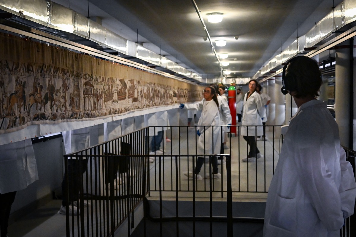 Workers and volunteers, rest before preparing to pack the Bayeux Tapestry in a crate for transfer to the British Museum, at the Bayeux Tapestry Museum, in Bayeux, northwestern France, on September 18, 2025. Photo by Lou Benoist / Pool / AFP
