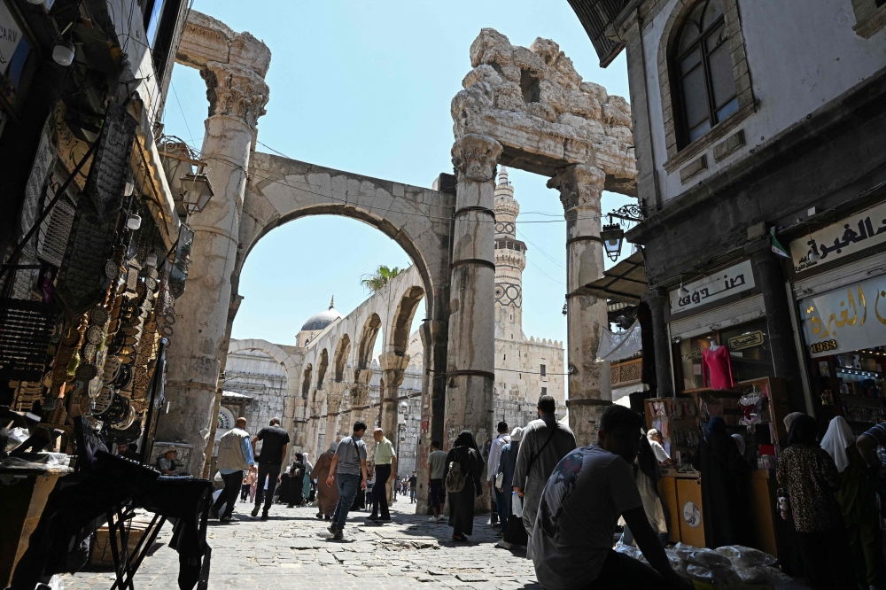 Shoppers walk through an old market area near the Umayyad Mosque in Damascus on July 9, 2026. (Photo by Louai Beshara / AFP)