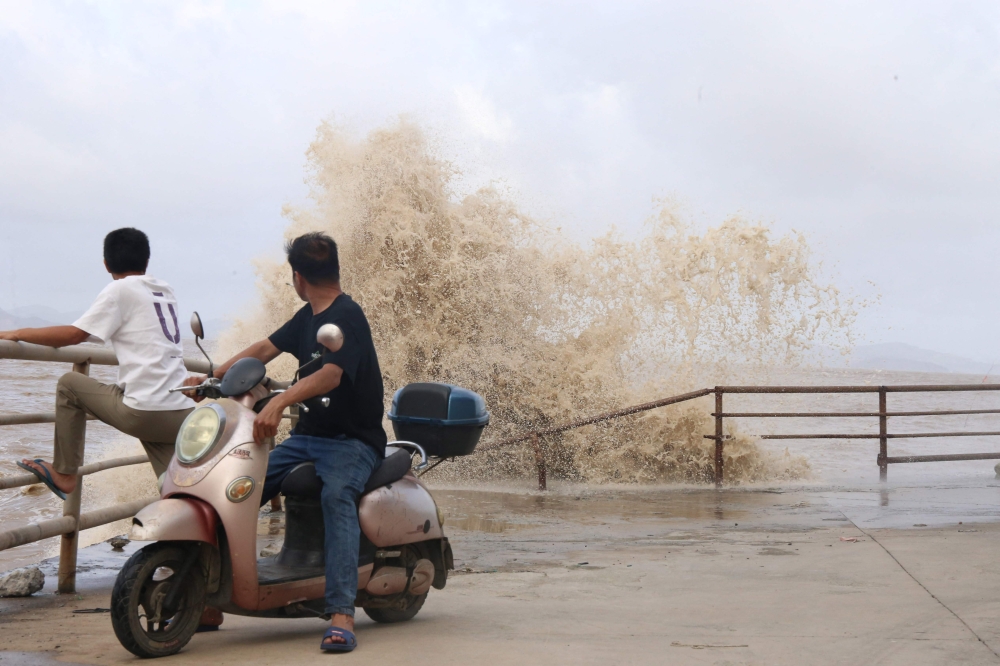 People look on as large waves crash against the coast amid weather patterns from approaching Typhoon Bavi in Wenling city, Taizhou, China's eastern Zhejiang province on July 10, 2026. (Photo by CN-STR / AFP)
 