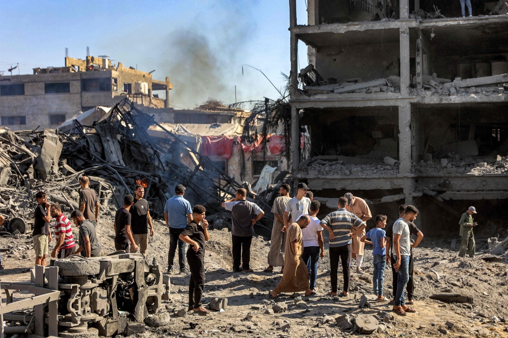 People gather by the rubble of destroyed buildings following an Israeli strike on an industrial area in Gaza City on July 12, 2026. (Photo by Omar Al-Qattaa / AFP)