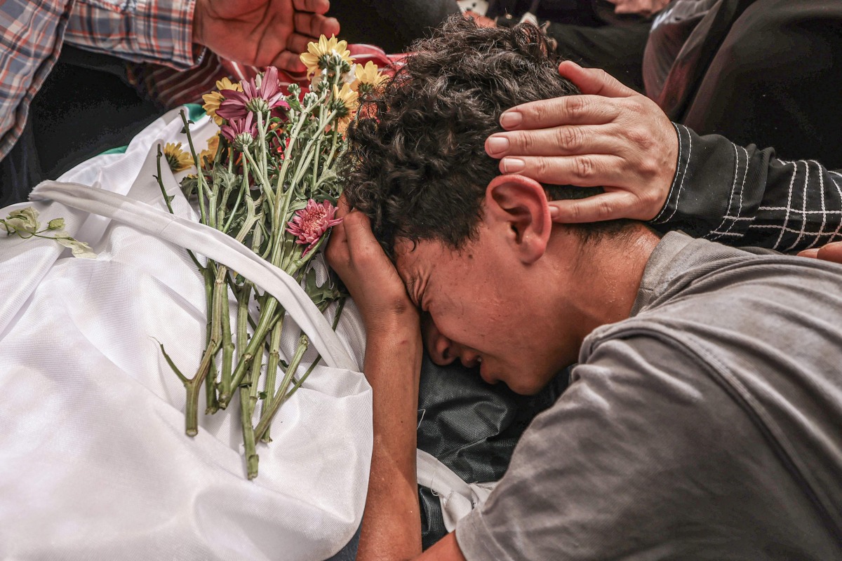 A relative mourns over the body of 17-year-old Fadi al-Naasan during his funeral in the village of Al-Mughayyir, east of Ramallah in the Israeli-occupied West Bank, on July 18, 2026. (Photo by JAAFAR ASHTIYEH / AFP)