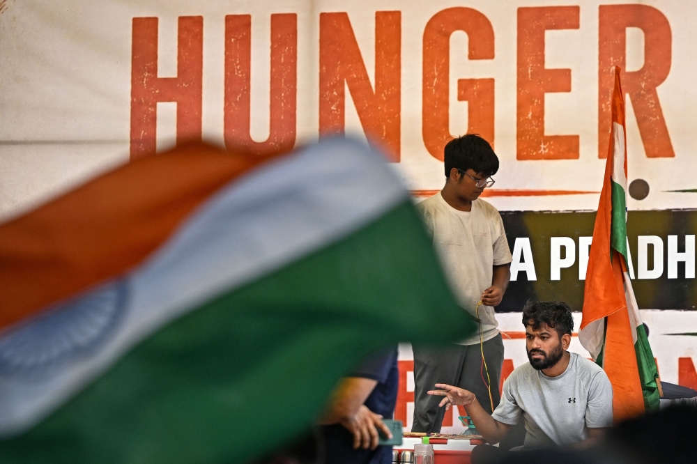 Cockroach Janta Party (CJP) founder Abhijeet Dipke (R) sits on an indefinite hunger strike demanding the resignation of India's Education Minister Dharmendra Pradhan over alleged NEET examination irregularities in New Delhi on July 19, 2026. (Photo by Sajjad Hussain / AFP)
 