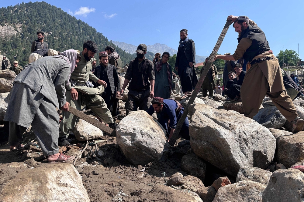 Afghan men search the debris of destroyed shops following flash floods in Parun town in Afghanistan's Nuristan province, on July 21, 2026. (Photo by AFP)