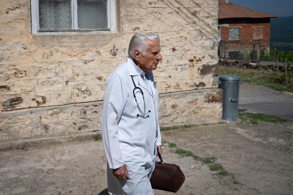 Dr. Apostolov, 90, a general practitioner, leaves his consulting room to visit a patient in the village of Skrat, in the foothills of the Belasitsa Mountains on July 15, 2026. (Photo by Nikolay Doychinov / AFP)