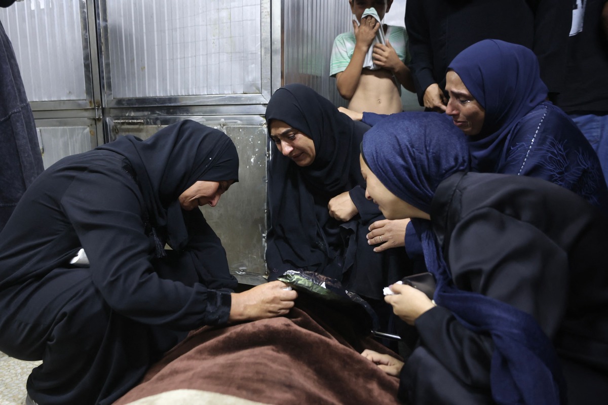 Mourners weep over the body of one of the Palestinian who died after an Israeli airstrike targeted a residential apartment in the Sabra neighborhood of Gaza City on July 21, 2026. (Photo by Omar AL-QATTAA / AFP)