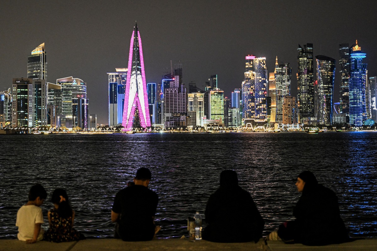 People sit facing the high-rise buildings at the Doha corniche promenade on July 21, 2026. (Photo by Mahmud Hams / AFP)

