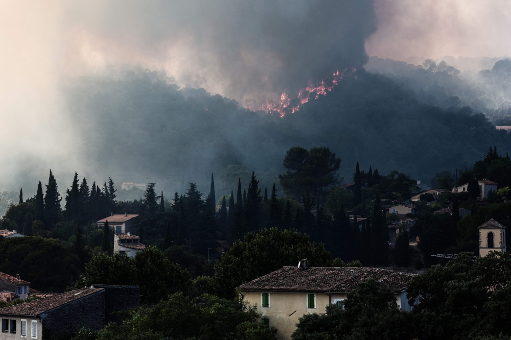 Flames spread on the hills surrounding Cotignac, southeastern France on July 23, 2026 during a wildfire. (Photo by Thibaud MORITZ / AFP)