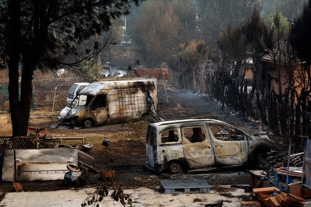 Burned cars sit in the yard of a home after a wildfire raged through Pelayos de la Presa, 65 kilometers west of Madrid, on July 26, 2026. (Photo by Oscar Del Pozo / AFP)