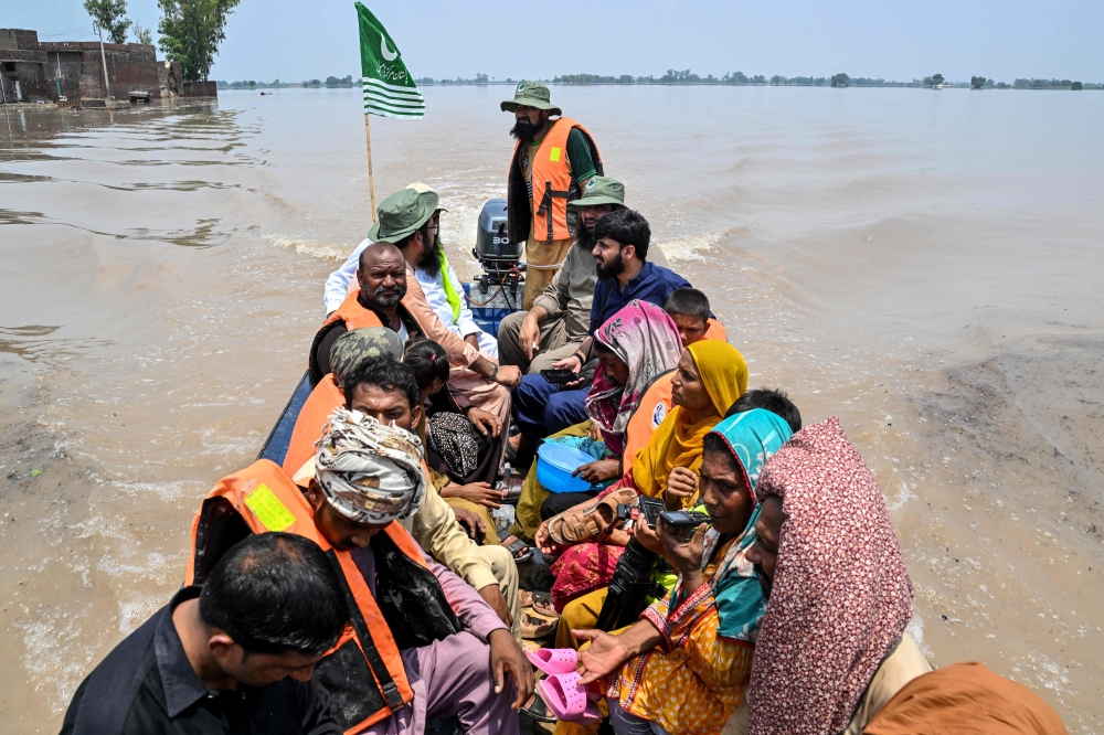 People sitting on a rescue boat ride through a flooded area after heavy monsoon rains induced a rise in the water level of the River Ravi in Muridke on July 27, 2026. (Photo by Arif ALI / AFP)