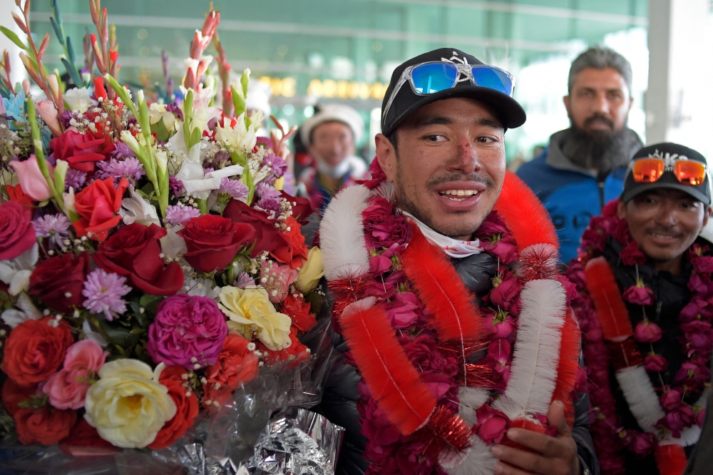 (Files) Nepal's climber Nirmal Purja (C) watches upon his arrival along with his team at the airport in Islamabad on January 21, 2021. (Photo by Farooq Naeem / AFP)