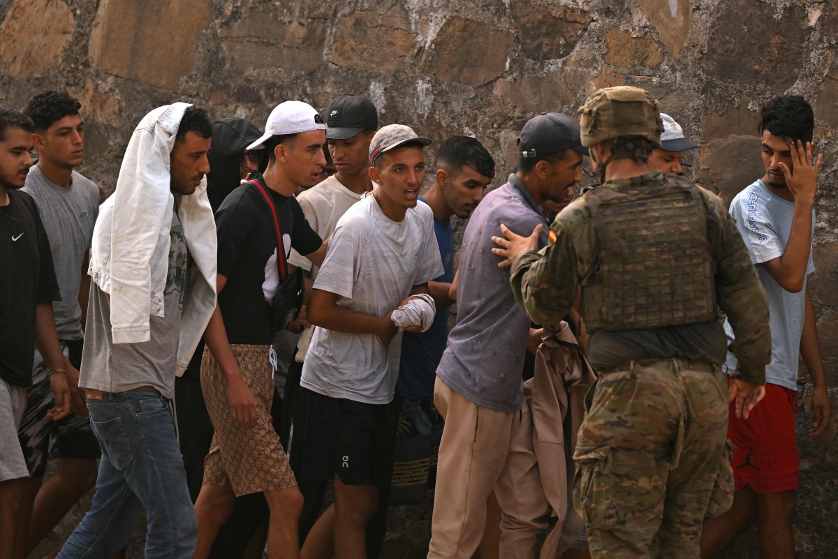A Spanish soldier controls a group of migrants on their way back towards the Moroccan border, following their illegal crossing into the Spanish enclave of Ceuta, on August 1, 2026 (Photo by JORGE GUERRERO / AFP)