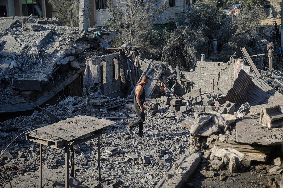A displaced Palestinian man walks across the debris of buildings destroyed in Israeli attacks in Deir al-Balah, central Gaza Strip on August 1, 2026. (Photo by Eyad Baba / AFP)