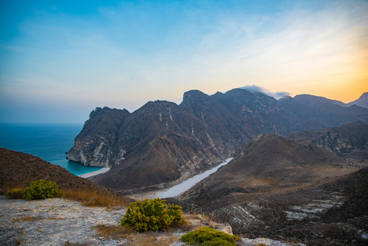 A photo of a beach, sea, and mountains in Oman