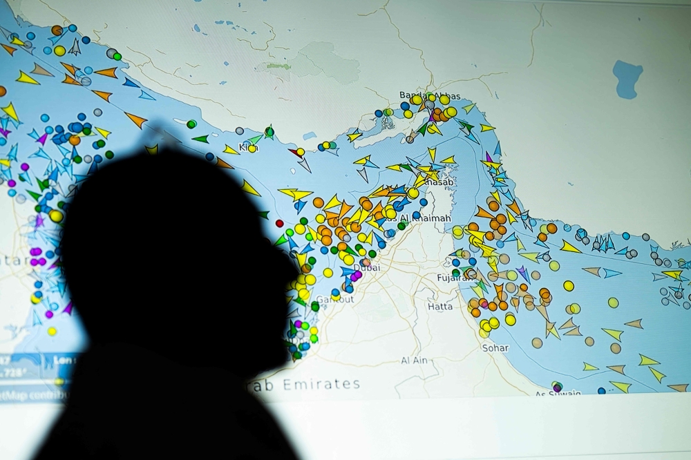 (Files) A photo illustration taken in Nicosia on May 4, 2026, shows a person in front of a large screen displaying vessel movements in the Strait of Hormuz on a ship-tracking website. (Photo by AFP)