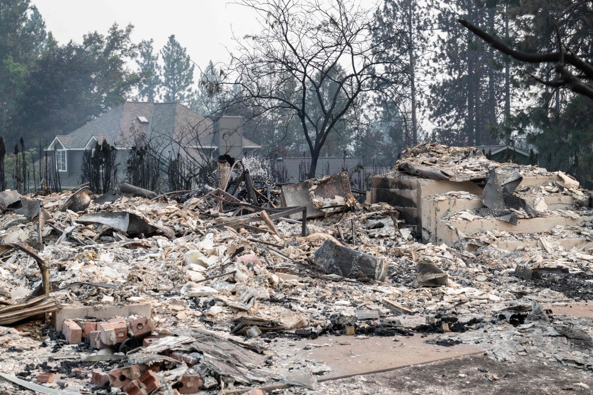 The rubble of a burned out residential home smolders in the Balboa neighborhood of Spokane, Washington, on August 2, 2026. Photo by Erick Doxey / AFP