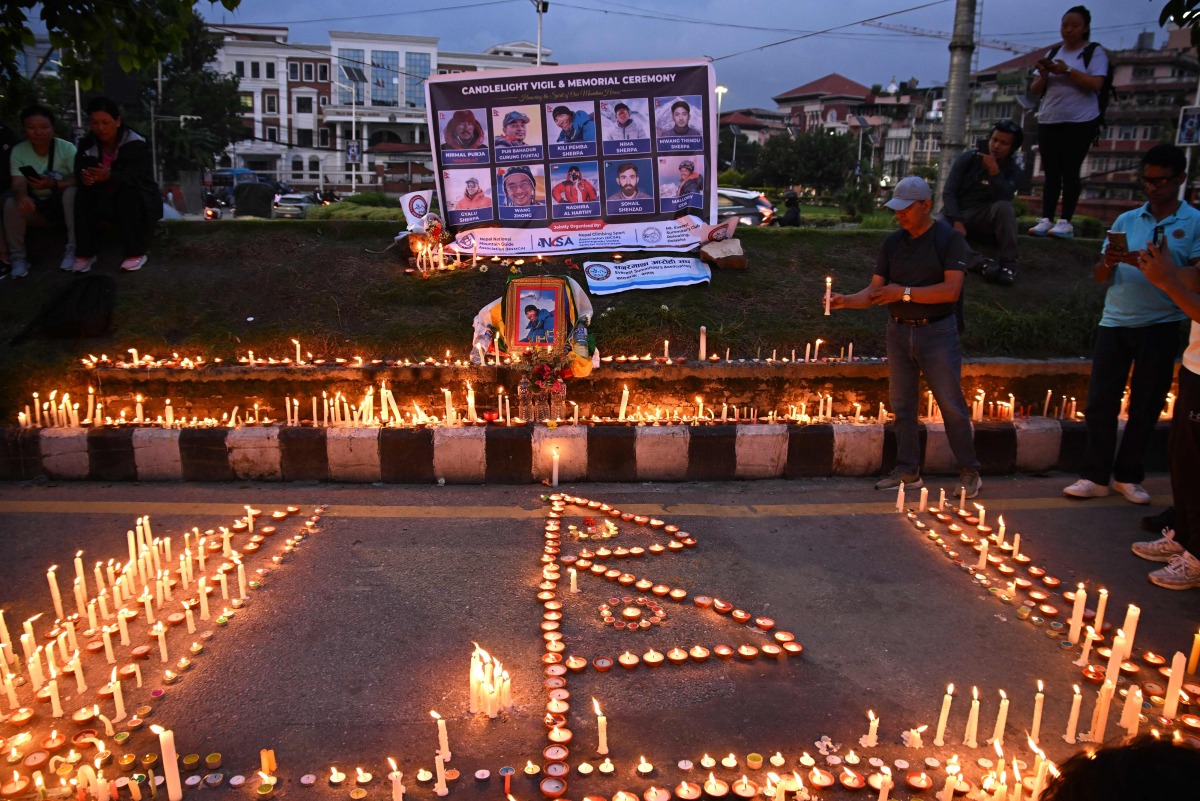 Mourners light candles before the portraits of mountaineer Nirmal Purja and his companions, who were killed in an avalanche in Pakistan, during a memorial ceremony in Kathmandu on August 4, 2026. (Photo by Prakash MATHEMA / AFP)