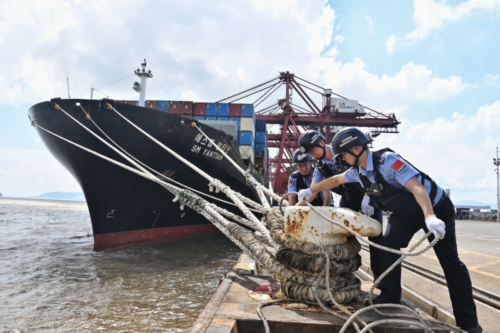 Police officers check the mooring lines of a vessel ahead of a typhoon in Beilun District of Ningbo City, east China's Zhejiang Province, (Photo by Hu Jiajie/Xinhua)