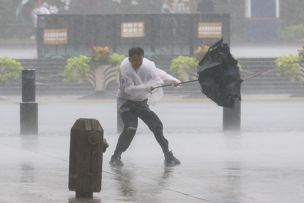A man holds tightly onto an umbrella that is blown open by the wind amid rain at Huangpu District of Shanghai, east China, on Aug. 9, 2026. (Xinhua/Wang Xiang)