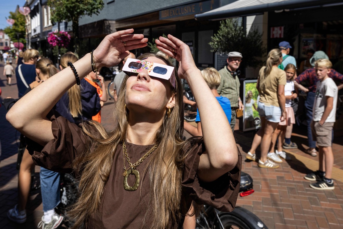 A woman wears eclipse glasses in Almelo, eastern Netherlands on August 11, 2026 on the eve of a partial solar eclipse. Photo by Vincent Jannink / ANP / AFP