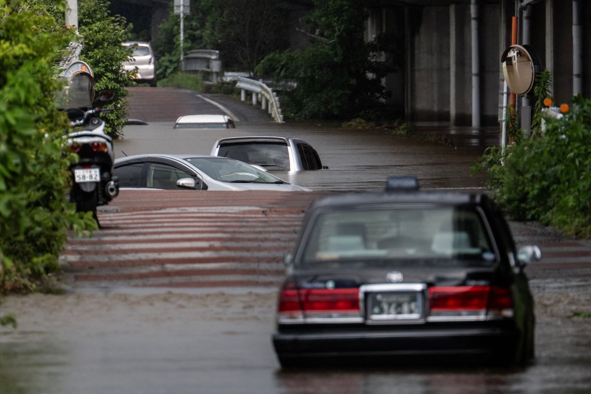 Abandoned cars are seen partially submerged on a flooded road in Sakura, Chiba prefecture on August 14, 2026. Photo by ANDREW CABALLERO-REYNOLDS / AFP