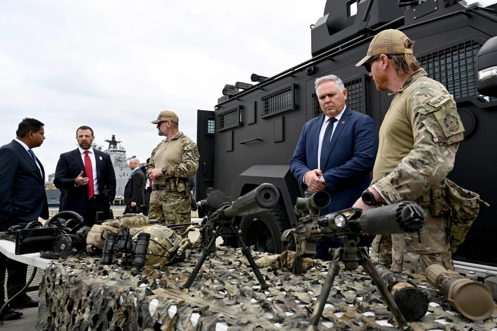 Australian Defence and Border Force officials brief Canadian Minister of Public Safety Gary Anandasangaree (L), US Secretary of Homeland Security Markwayne Mullin (2nd L), and New Zealand Police Minister Mark Mitchell (2nd R) on sniper rifles during a capability demonstration on Garden Island in Sydney on August 26, 2026, at an event held as part of the Five Country Ministerial (FCM) meeting. (Photo by Saeed KHAN / AFP)